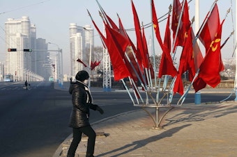 caption: A person passes by a bouquet of Workers Party flags along a main street of the Central District in Pyongyang, North Korea, last week.