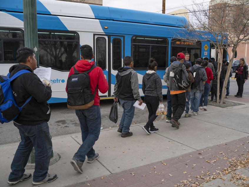 caption: Central American migrants make their way to local buses after being dropped off in El Paso, Texas, by Immigration and Customs Enforcement on Christmas Day.