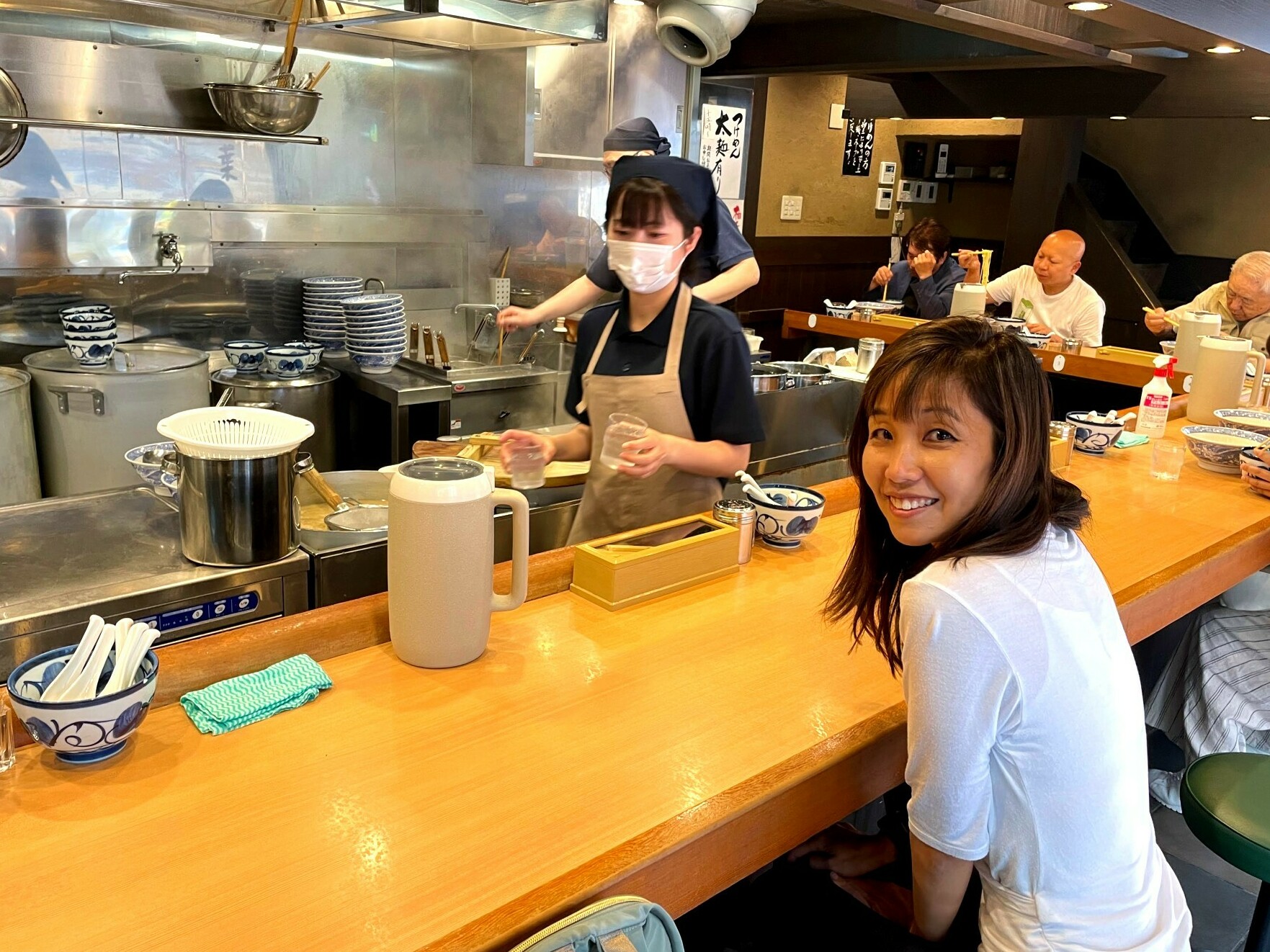 caption: The author awaits a bowl of ramen noodles in a Tokyo restaurant.