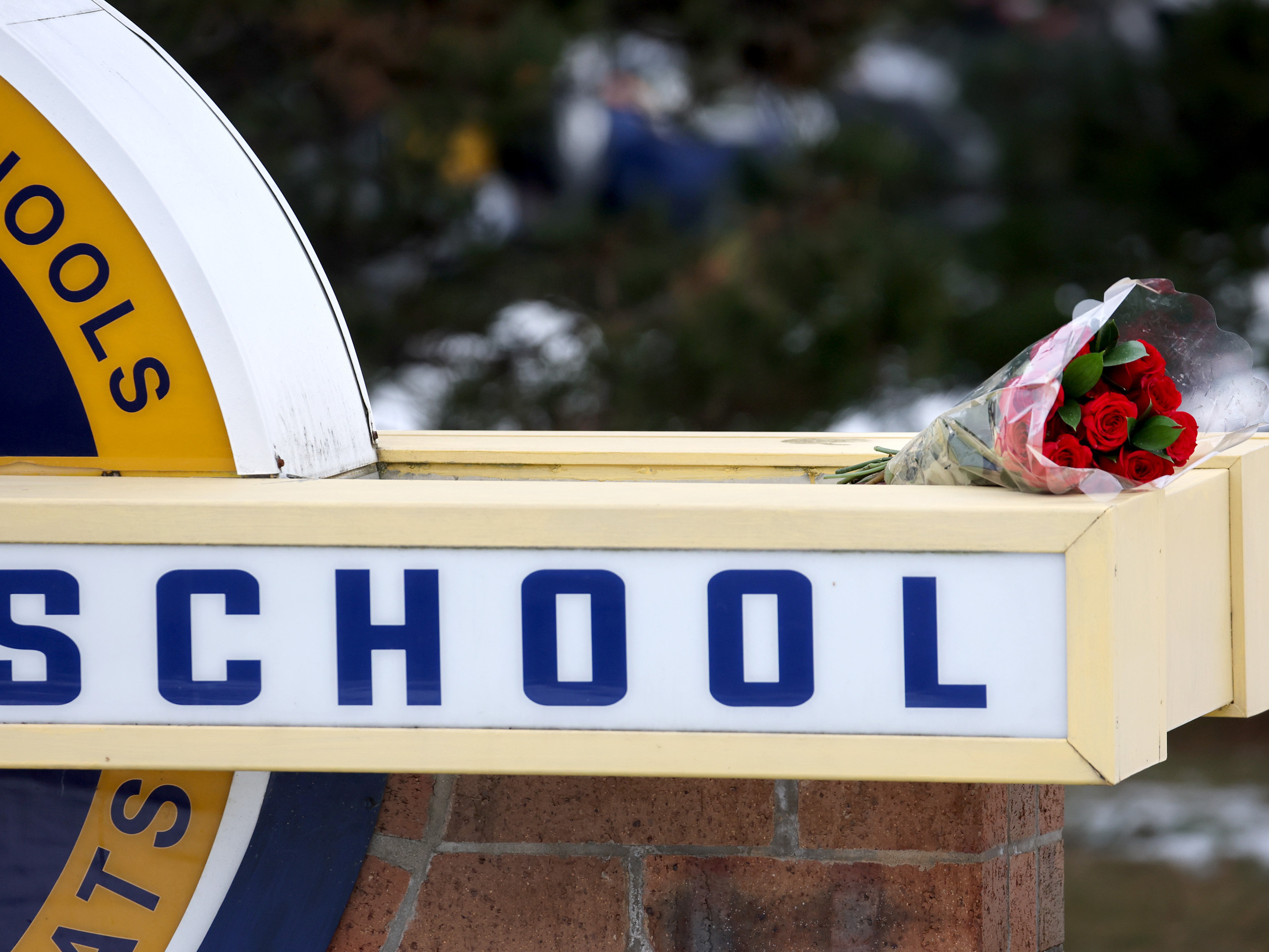 caption: Flowers sit a sign outside Oxford High School a day after a deadly shooting at the school on Dec. 1 in Oxford, Mich.