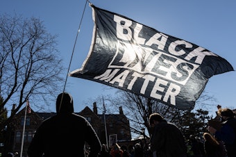 caption: A man holds a Black Lives Matter flag during a March protest in St. Paul, Minn. Support for Black Lives Matter surged after protests following George Floyd's death. Activists charge that disparaging posts targeting BLM are part of an overall effort to undermine the movement and its message.