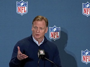 caption: NFL Commissioner Roger Goodell speaks to the media on March 28 in Phoenix. The attorneys general of New York and California announced Thursday that they are investigating allegations of workplace discrimination by the pro football league.