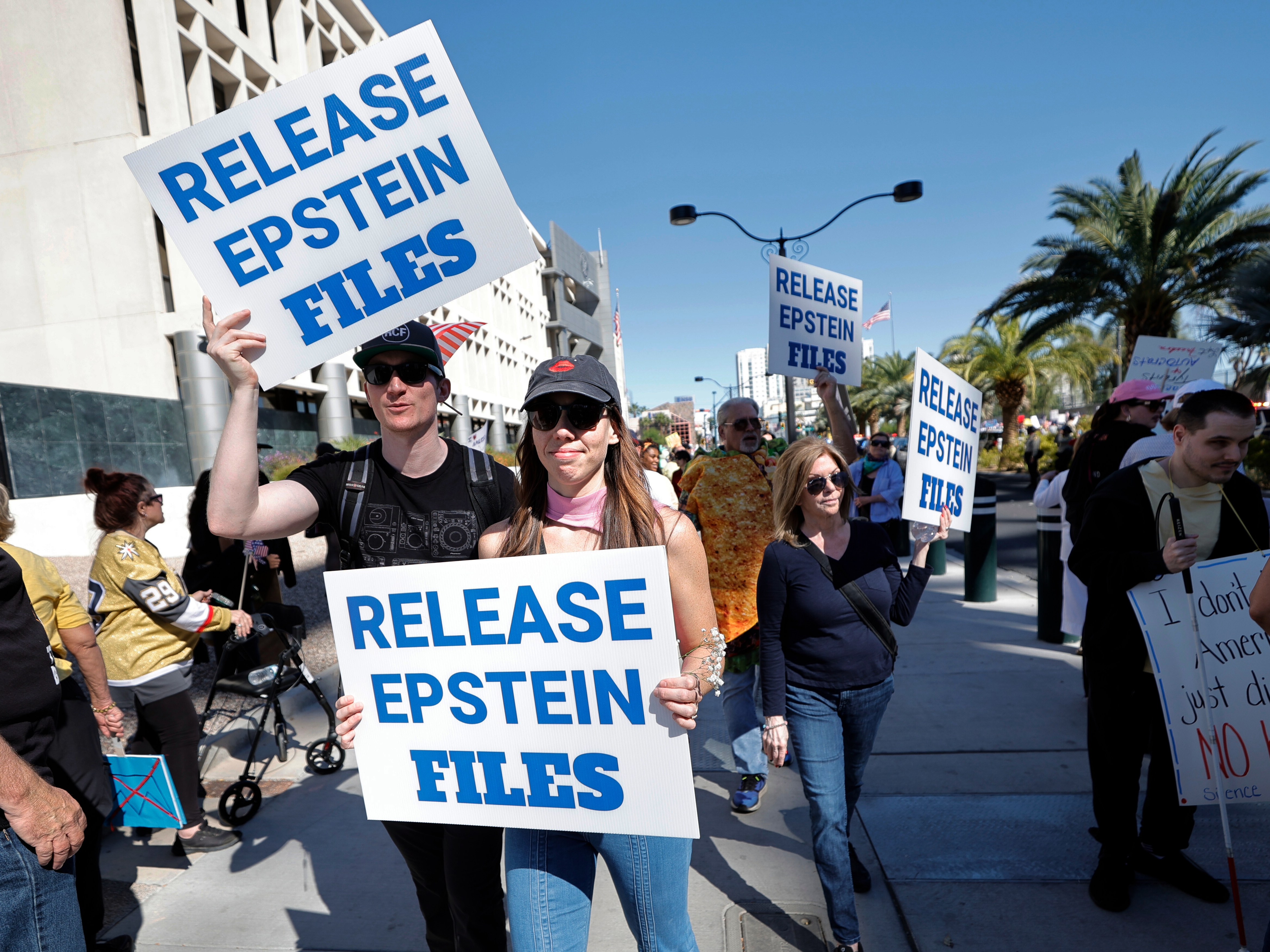 caption: Demonstrators hold signs asking for the release of the Epstein files during a "No Kings" protest in downtown Las Vegas on Oct. 18, 2025.