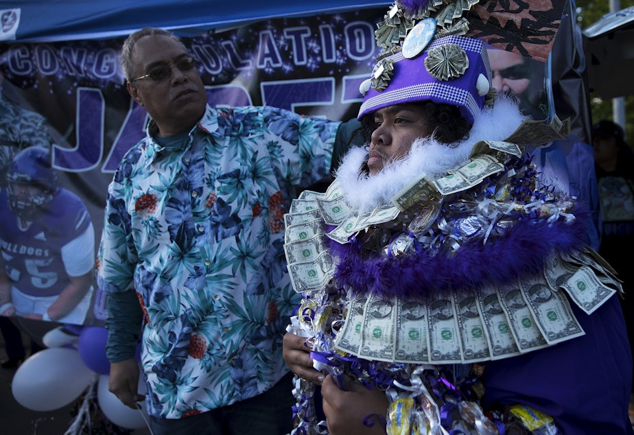 caption: Eduardo Taualo assists his son, Jabez Taualo, with a cultural headdress honoring their families heritage and High Chiefs of Samoa, ahead of taking family portraits after the Garfield High School in-person commencement ceremony for the class of 2021, on Tuesday, June 15, 2021, at Memorial Stadium in Seattle. "It's a true honor to be here today," said Taualo.