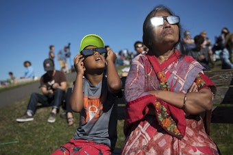 caption: Ayush Jakhotia, 7, left, watches the solar eclipse with his grandmother, Radha Jakhotia, right, on Monday, from Gas Works Park, in Seattle. 