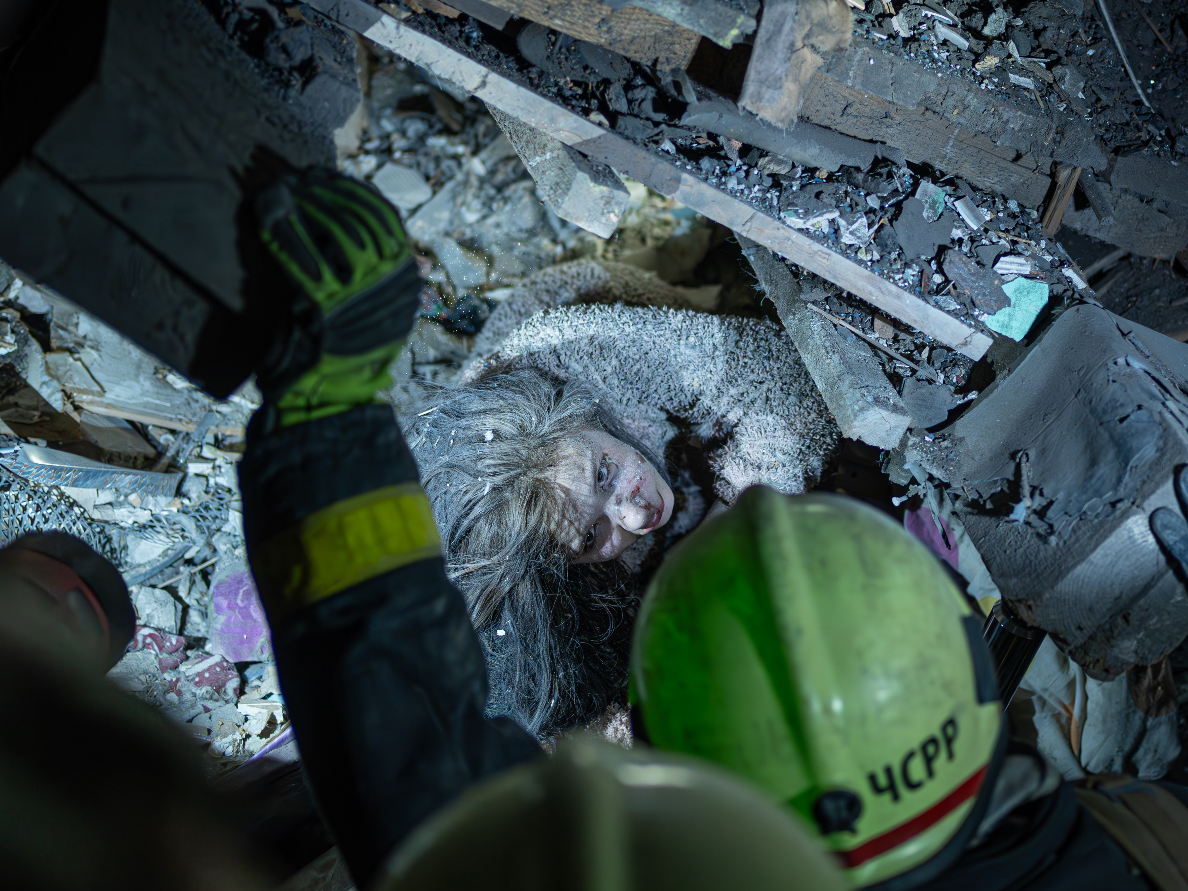 caption: A Ukrainian woman looks at rescuers as they try to pull her out from under the rubble of a building after a Russian military strike on Kyiv, Ukraine, on Thursday. The strike occurred at 1 a.m., when most people were asleep. So far, nine people have been confirmed dead and more than 70 injured. The rescue operation is ongoing.