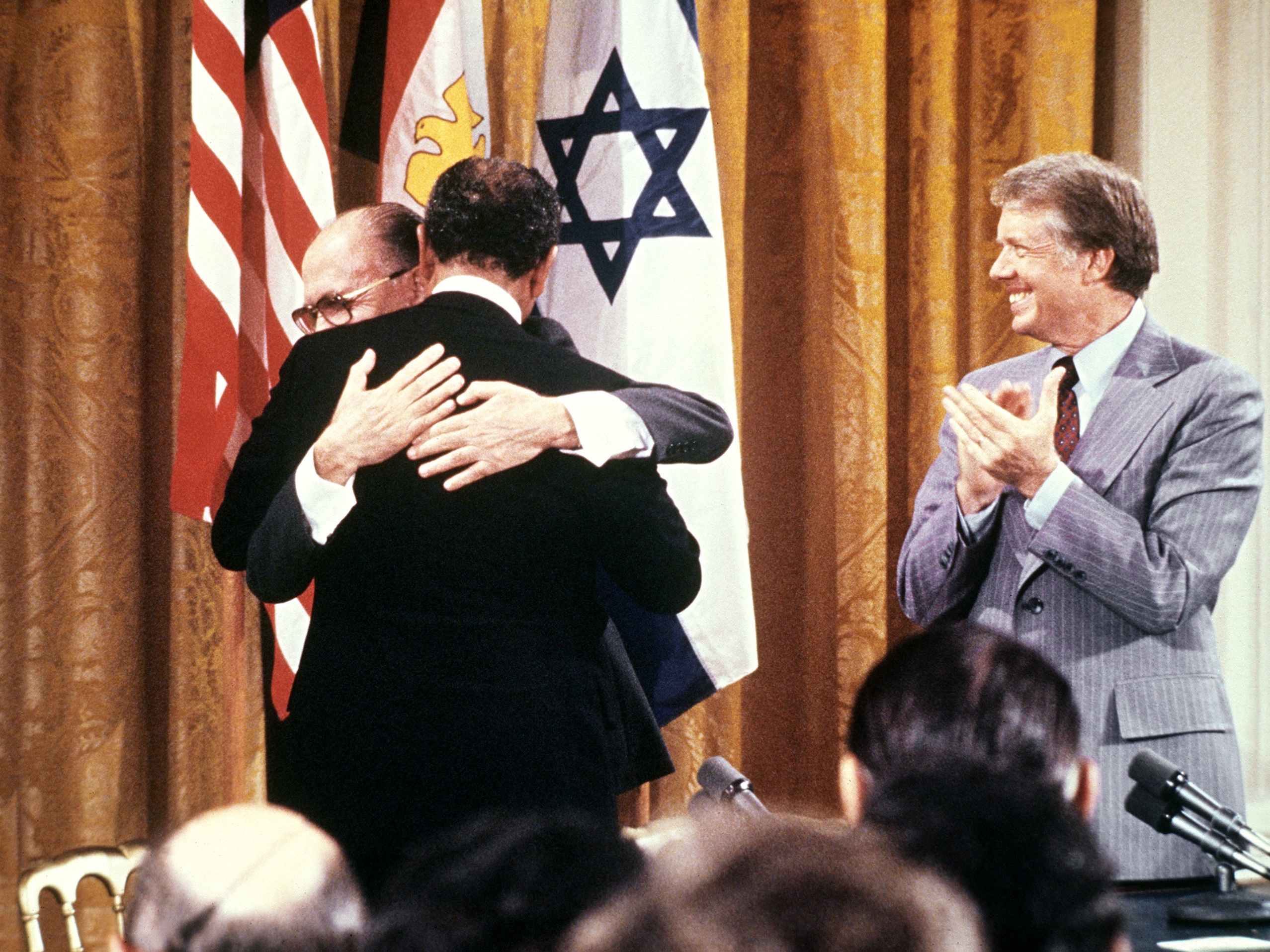 caption: Egyptian President Anwar al-Sadat (back to camera) and Israeli Premier Menachem embrace each other, on Sept. 17, 1978, after signing a peace agreement in the White House with US President Jimmy Carter.