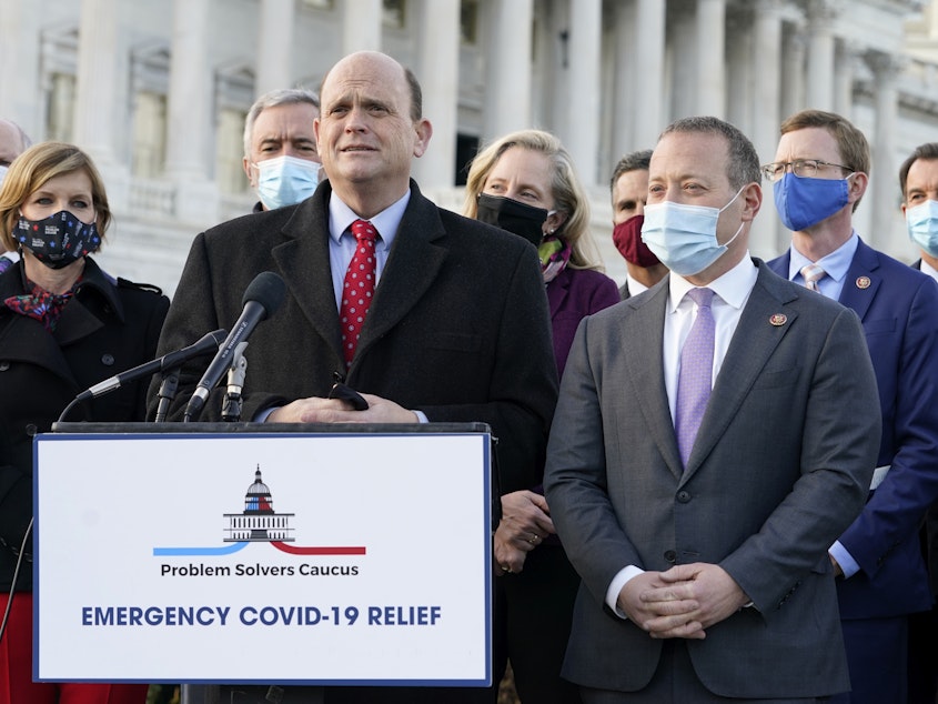 caption: Members of the bipartisan Problem Solvers Caucus — co-chairs Rep. Tom Reed, R-N.Y., at podium, and Rep. Josh Gottheimer, D-N.J., right — took credit for helping to break the logjam on an emergency COVID-19 relief bill.