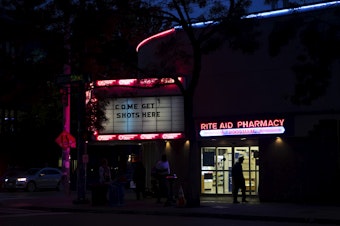caption: 'Come Get Shots Here' reads a sign outside of Rite Aid Pharmacy on Wednesday, August 18, 2021, along Broadway East in the Capitol Hill neighborhood of Seattle. 