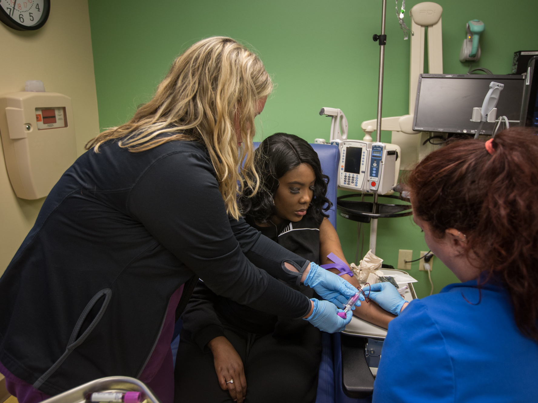 caption: As part of a clinical trial to treat sickle cell disease, Victoria Gray (center) has vials of blood drawn by nurses Bonnie Carroll (left) and Kayla Jordan at TriStar Centennial Medical Center in Nashville, Tenn.