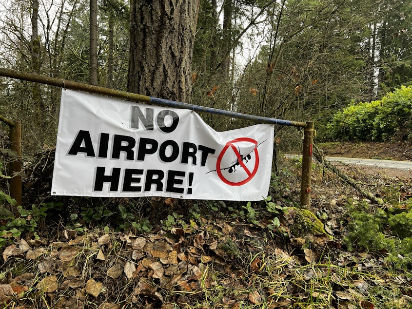 caption: Driving along Hwy 7 through southern Pierce County, you can see "No Airport Here!" signs on gates, front yards, and street corners.