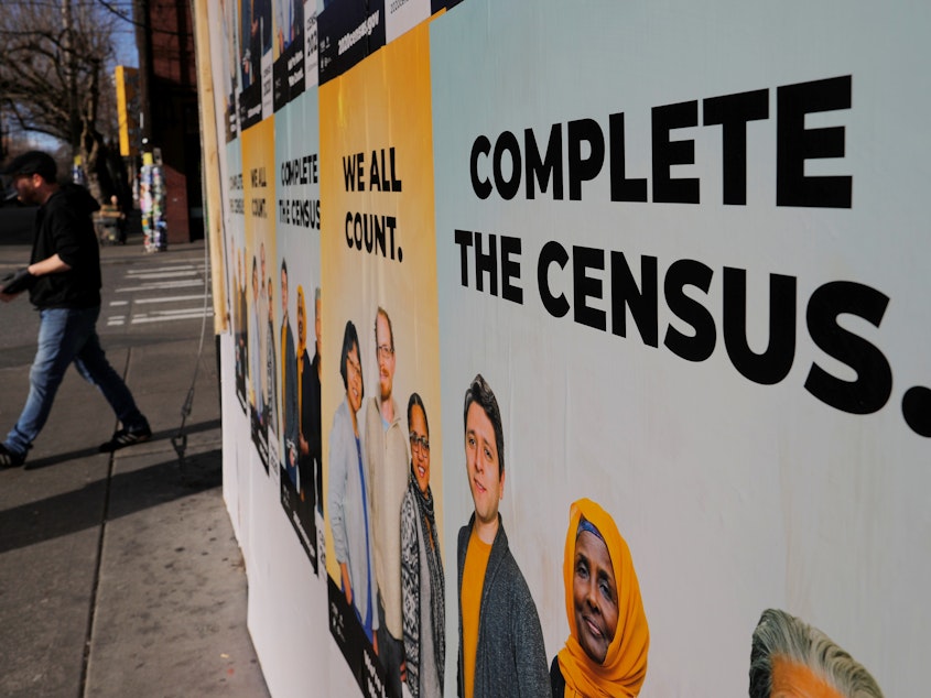 caption: Signs advertising the U.S. census cover a closed and boarded-up business in Seattle in 2020.