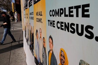caption: Signs advertising the U.S. census cover a closed and boarded-up business in Seattle in 2020.