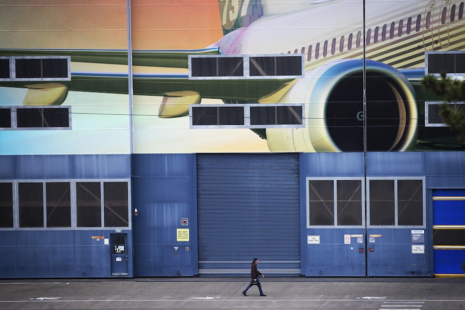 caption: A Boeing employee walks out of the Boeing Renton Factory after shift change on Monday, Dec. 16, 2019, in Renton.