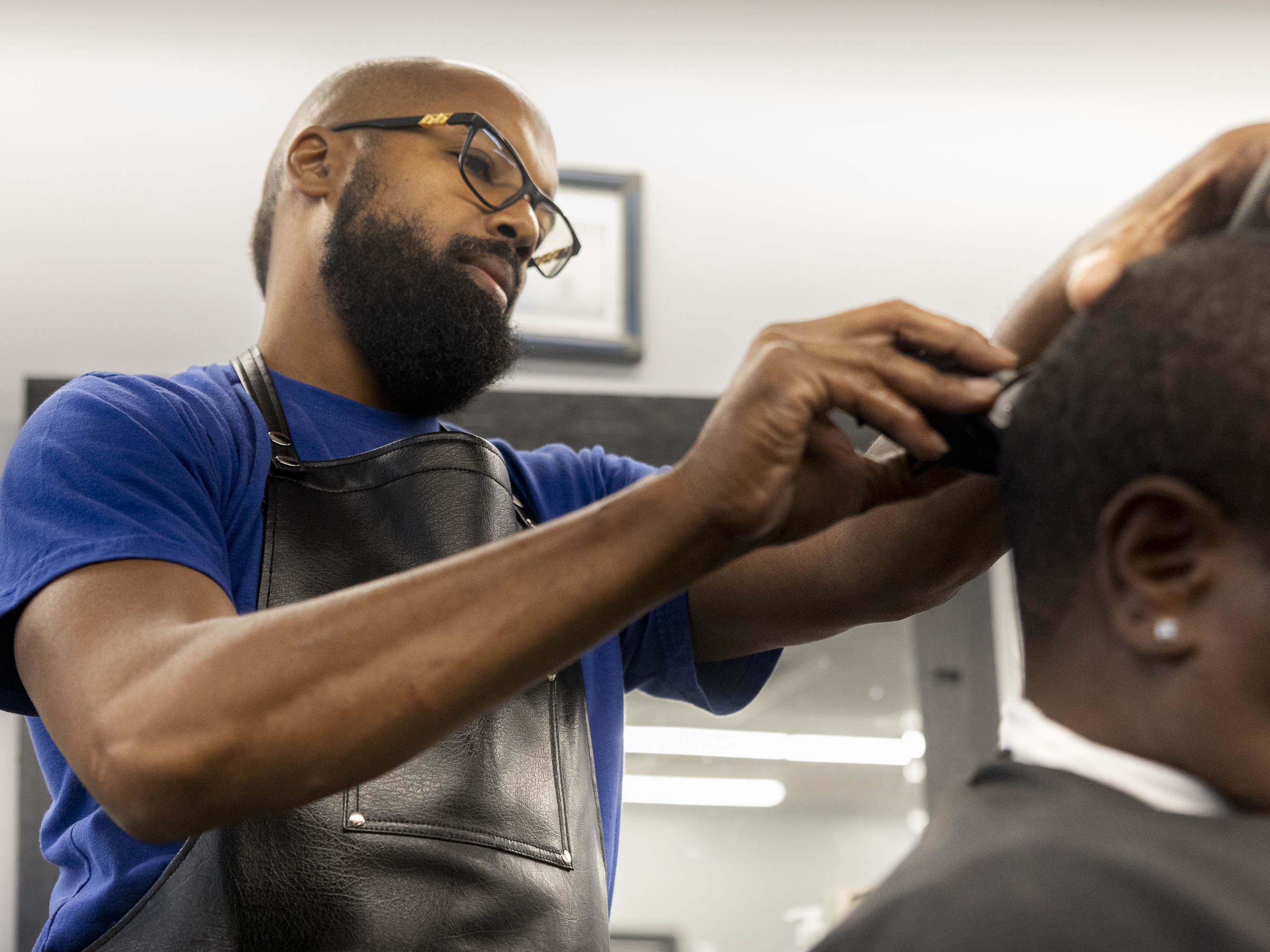 caption: Vann Cut Barber Shop owner Carnell Vann, Jr., 49, cuts a client's hair on September 30, 2025.