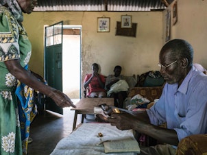 caption: A 2017 meeting of a rotating savings club formed in a village near Lake Victoria soon after every adult there was chosen to receive a monthly through GiveDirectly's experiment. The clubs have enabled recipients to convert their grants into lump sum payments: Each month the members put $10 into the communual pot — for a total of $100 — and a different person takes it home.
