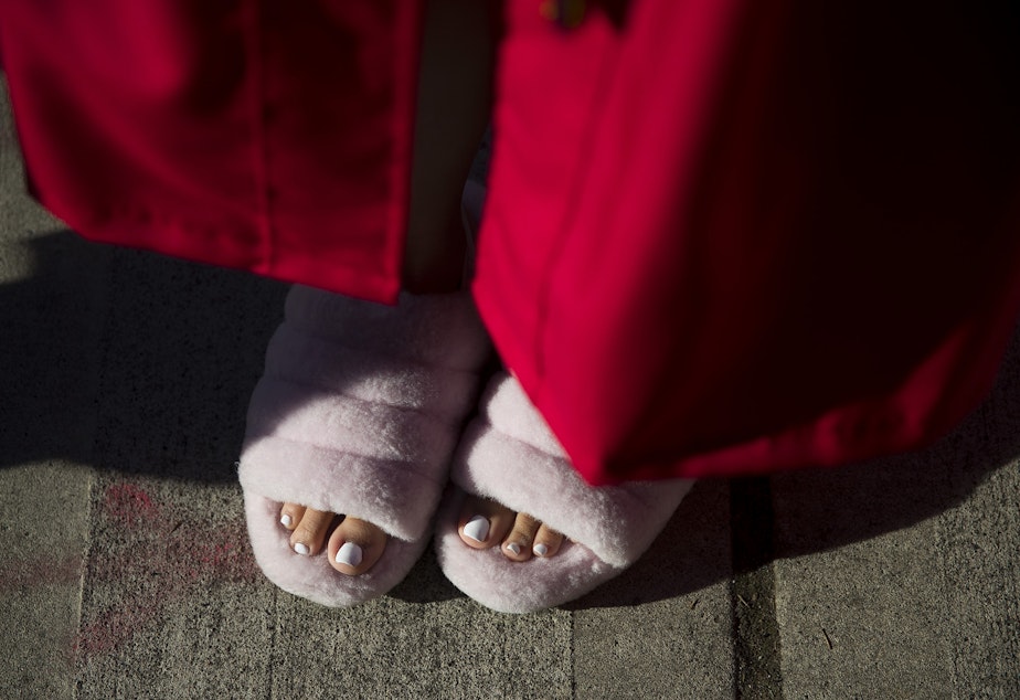 caption: Cleveland Stem High School senior Isabella Caldejon waits in line while wearing slippers before the start of the in-person commencement ceremony on Tuesday, June 15, 2021, at Memorial Stadium in Seattle.