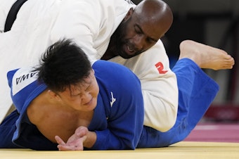 caption: Teddy Riner of France (top) and Hisayoshi Harasawa of Japan compete during their men's +100kg bronze medal judo match.