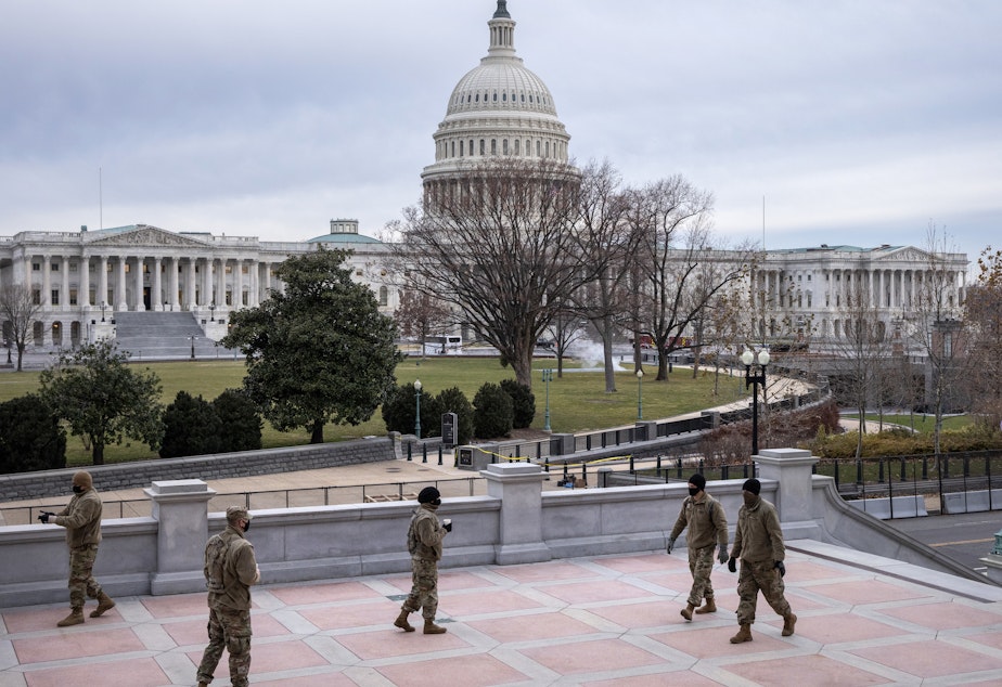 caption: Virginia National Guard troops stand watch near the U.S. Capitol Friday. House Speaker Nancy Pelosi has ordered the flags at the Capitol to be lowered to half-staff in Officer Brian Sicknick's honor.