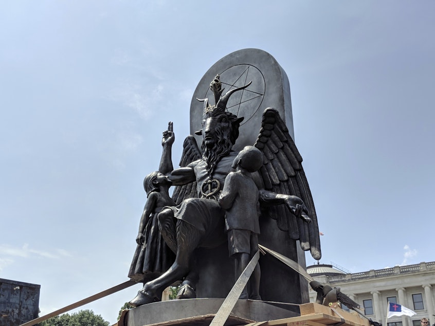 caption: The Satanic Temple's statue of Baphomet, seen at a rally in Little Rock, Ark. The organization says a statue in <em>Chilling Adventures of Sabrina</em> bears too close a likeness to its own work.