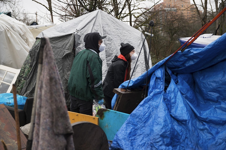 caption: Cass and Joscelyn DuVani redistribute resources including tents, sleeping bags, portable power packs, tarps, hot soup, clothing, and several other items to unhoused community members on Friday, March 5, 2021, near the intersection of 10th Avenue South and South Dearborn Street in Seattle. 