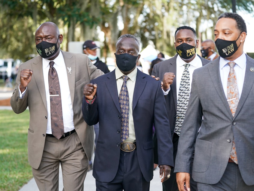 caption: Attorney Ben Crump, left, and Marcus Arbery Sr., the father of Ahmaud Arbery, second from left, arrive at the Glynn County Courthouse in Brunswick, Ga., as jury selection begins for the trial of the shooting death of Ahmaud Arbery on Monday.