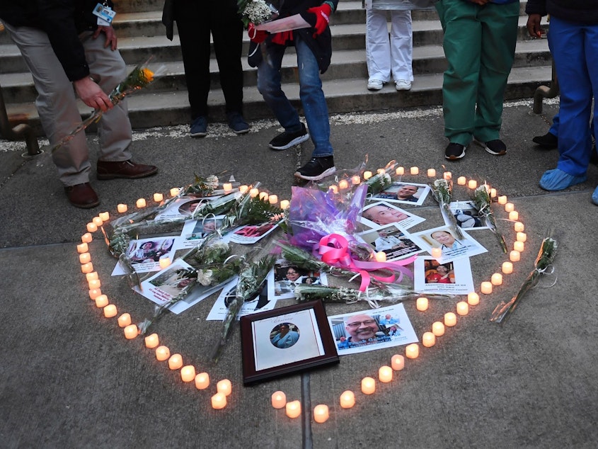 caption: Health care workers light candles outside Mount Sinai Hospital in New York City on April 10 as they mourn and remember their colleagues who have died during the COVID-19 pandemic.
