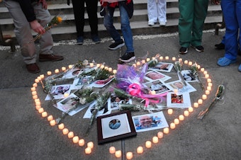 caption: Health care workers light candles outside Mount Sinai Hospital in New York City on April 10 as they mourn and remember their colleagues who have died during the COVID-19 pandemic.