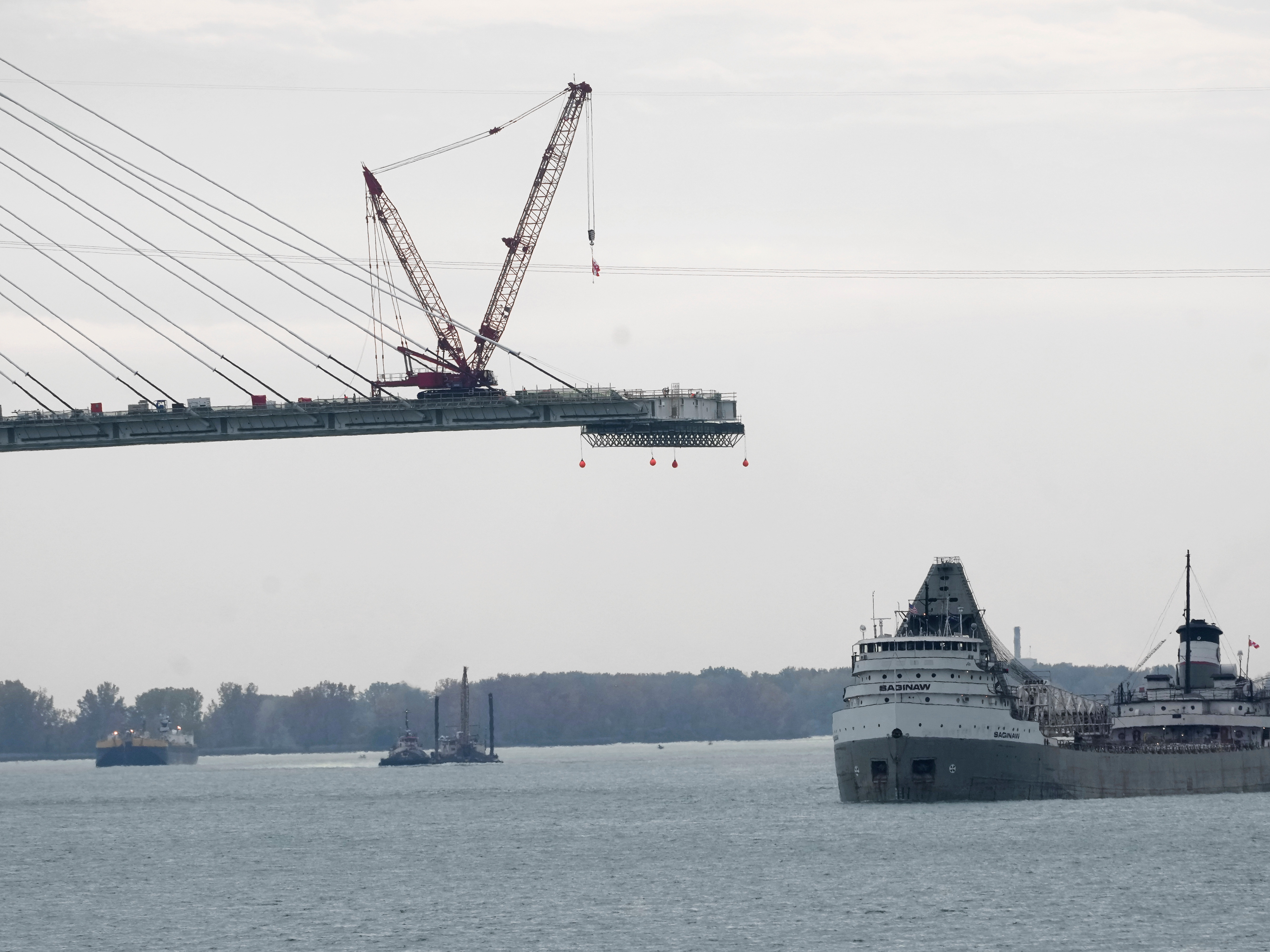 caption: FILE - The Saginaw passes construction on the Gordie Howe International Bridge connecting on the Detroit River connecting Windsor, Ontario and Detroit, Oct. 25, 2023.
