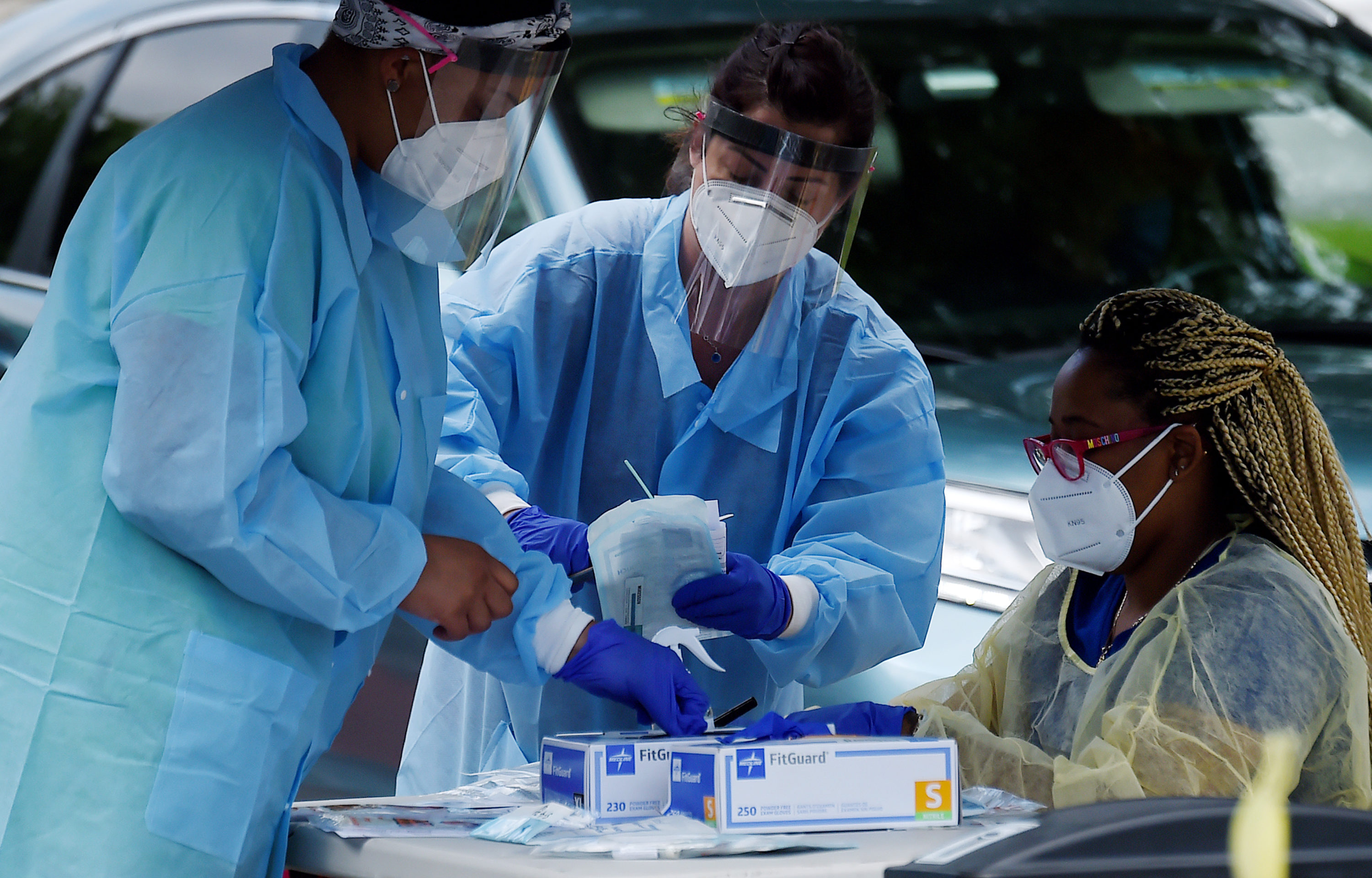 caption: Health workers prepare to give people free COVID-19 tests. (OLIVIER DOULIERY/AFP via Getty Images)