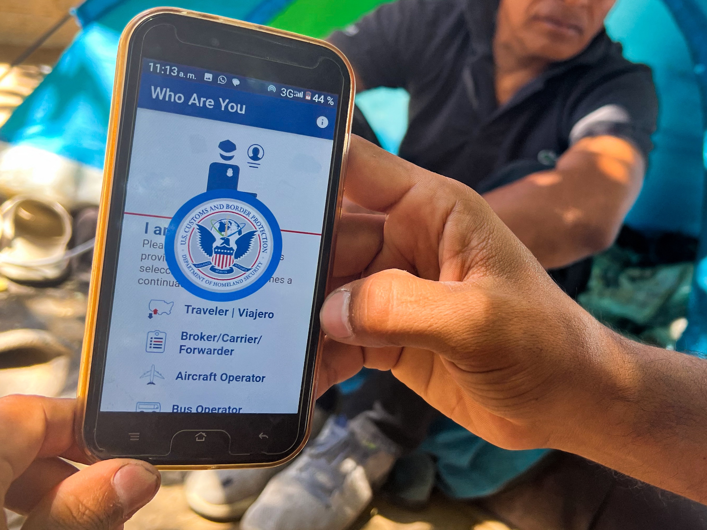 caption: A migrant at the U.S.-Mexico border shows the CBP One App from the U.S. Customs and Border Protection agency that is used to apply for an appointment to apply for asylum.