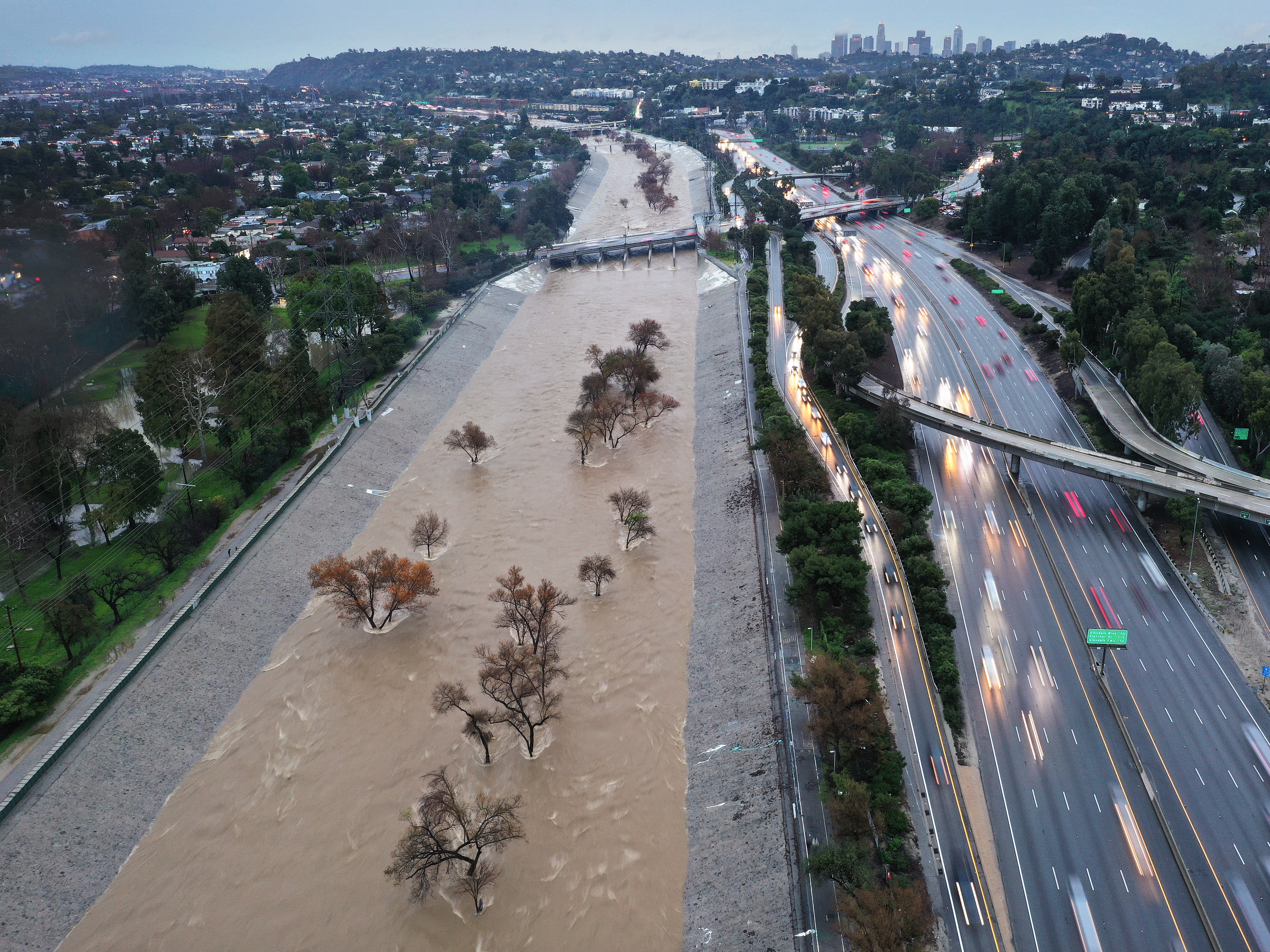 caption: An aerial view of the Los Angeles River swollen by runoff from a long-duration atmospheric river storm in February of 2024 in Los Angeles, California.