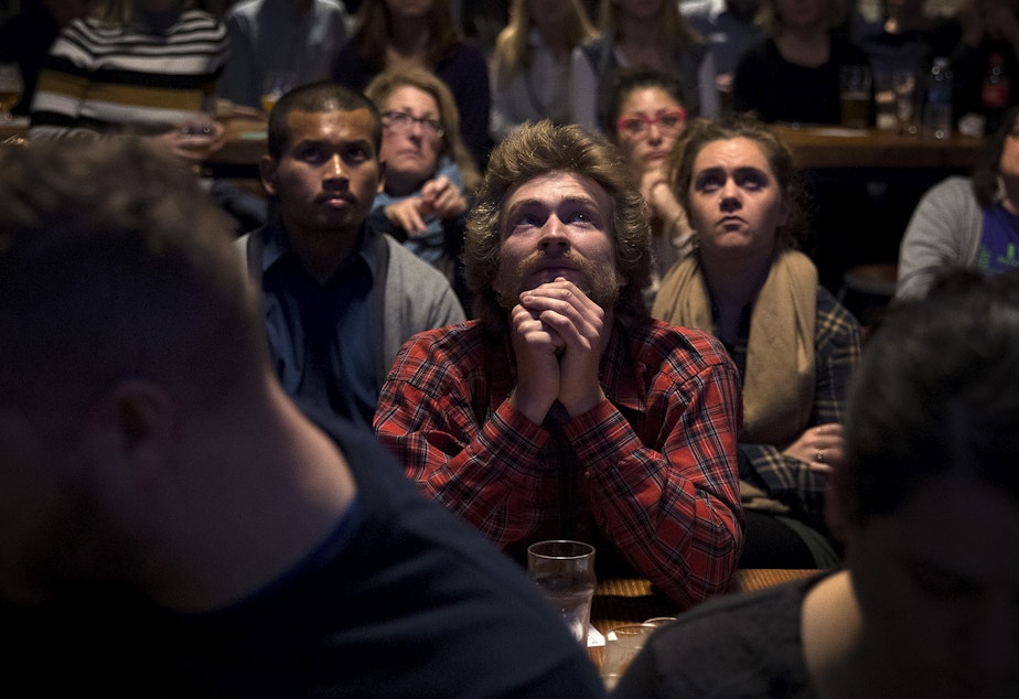 caption: Jacob Mandell watches a mayoral debate during a viewing party on Tuesday, October 24, 2017, at Optimism Brewing Company in Seattle.