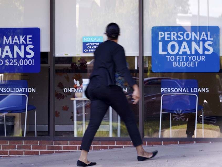 caption: A woman walks past a personal finance loan office in October 2020 in Franklin, Tenn.