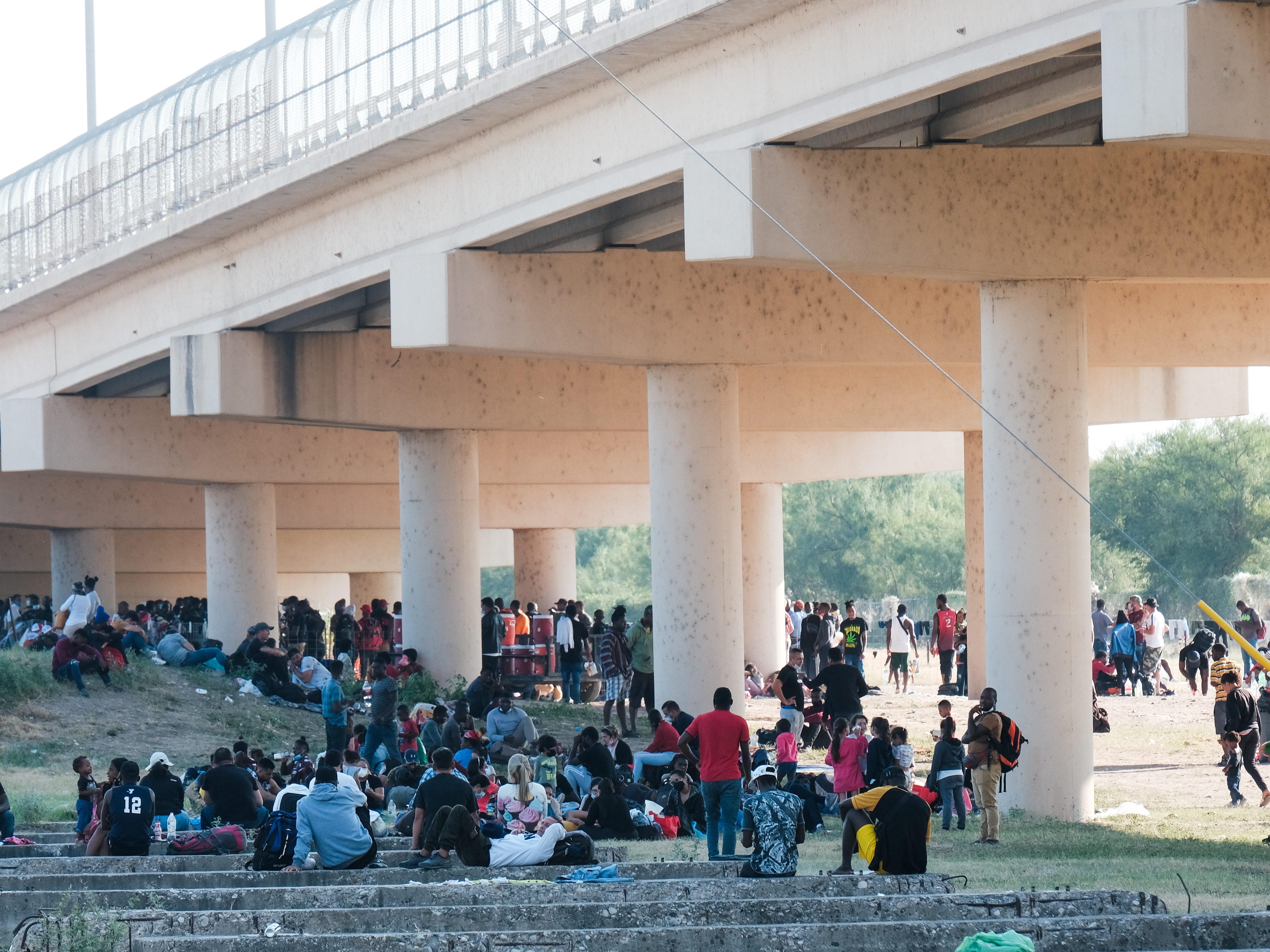caption: Migrants at the Rio Grande near the port of entry in Del Rio, Texas, on Saturday.
