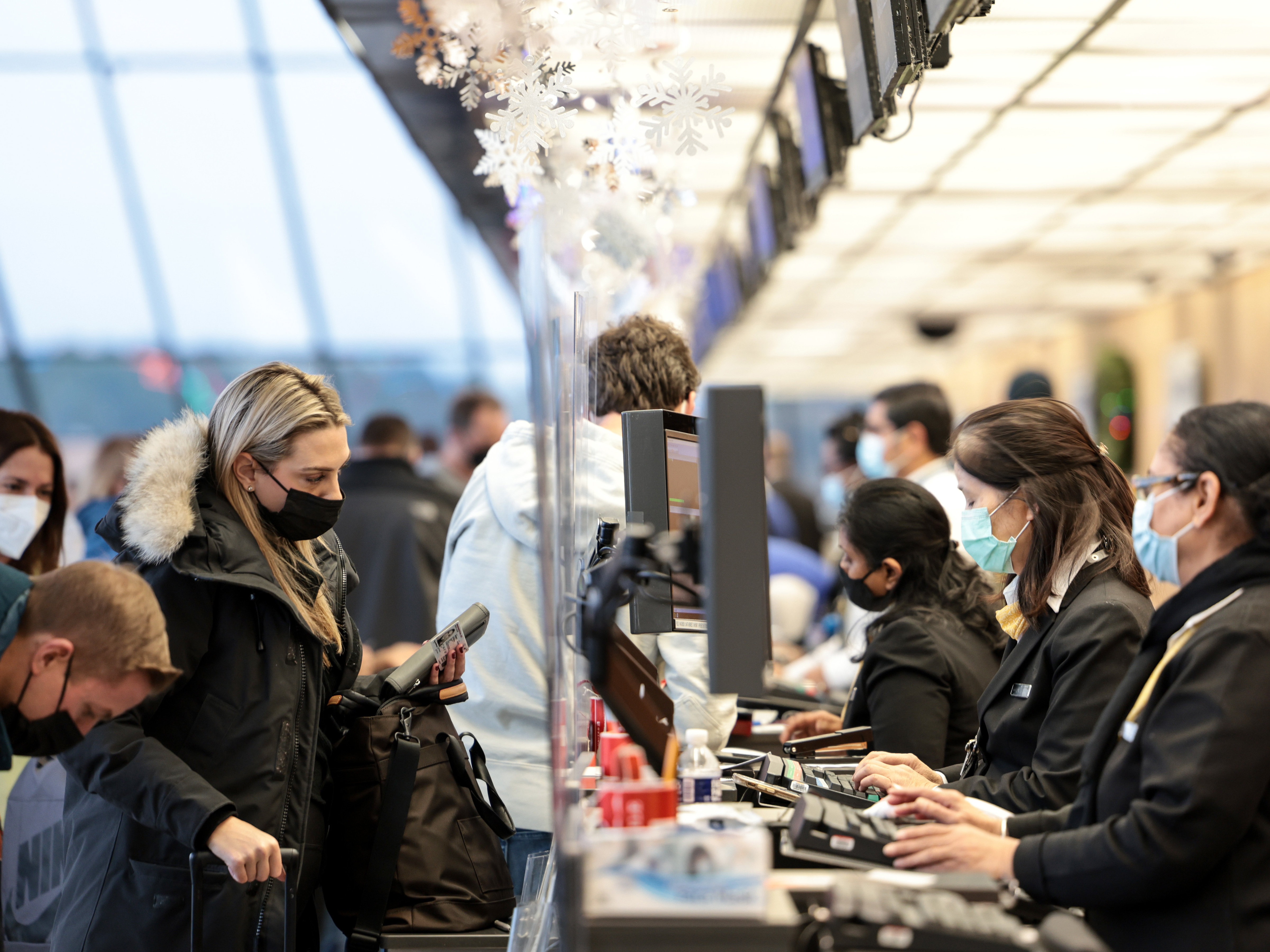 caption: A woman checks in for her flight at a United Airlines counter at Dulles International Airport on December 27, 2021.