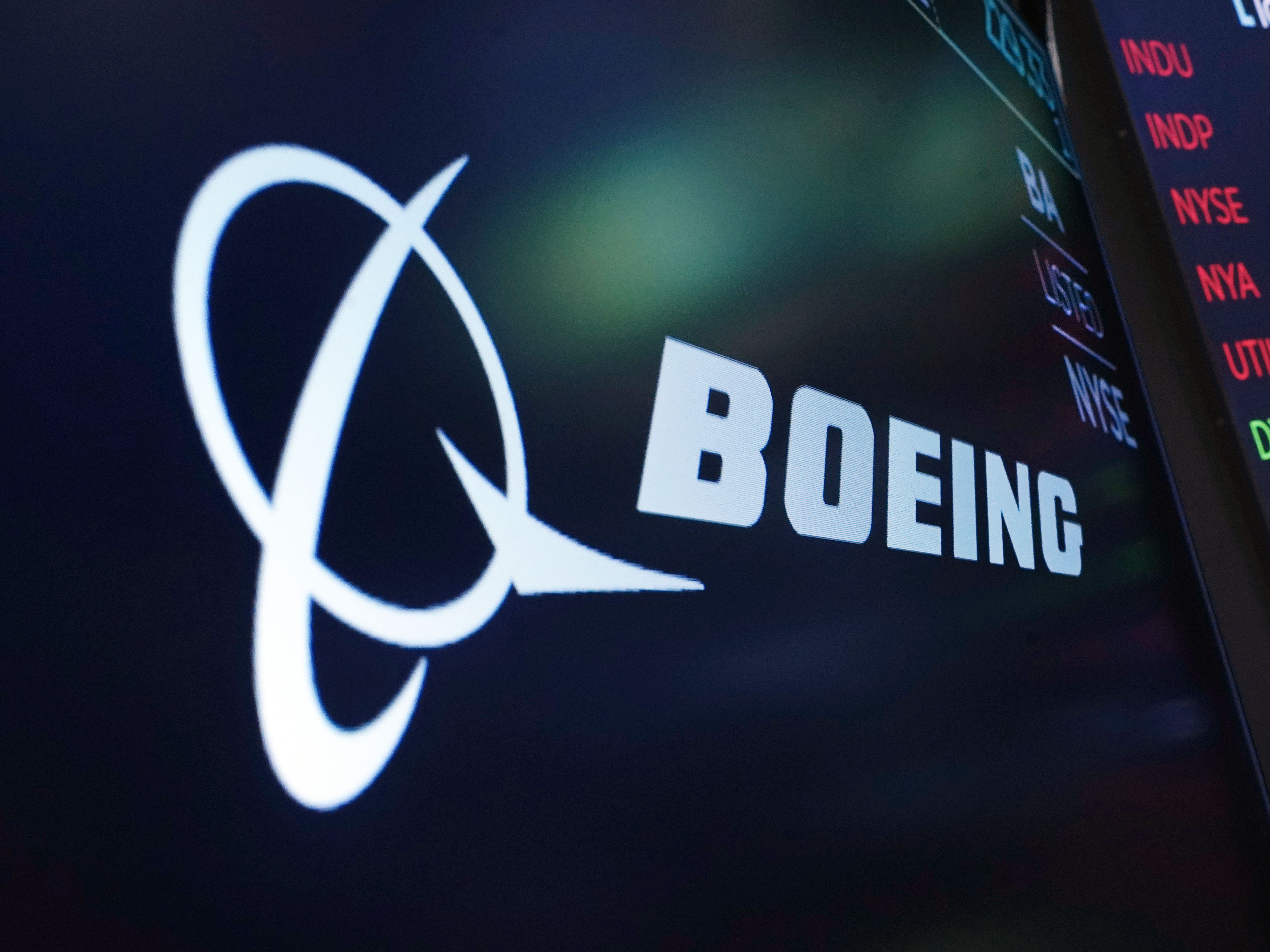 caption: The logo for Boeing appears on a screen above a trading post on the floor of the New York Stock Exchange on July 13, 2021.