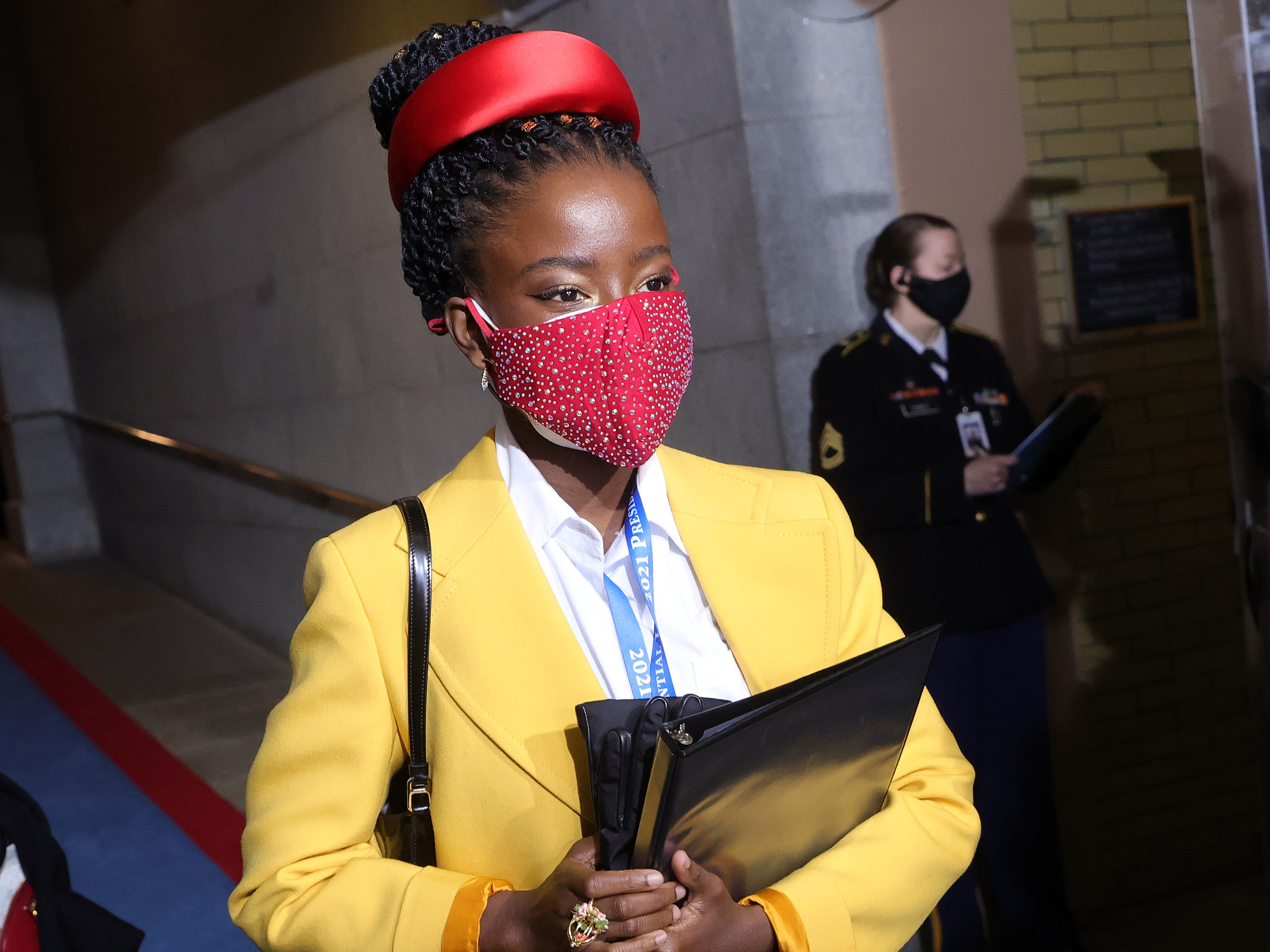 caption: National youth poet laureate Amanda Gorman arrives at the inauguration, dressed head-to-mask-to-toe in bright, primary colors.