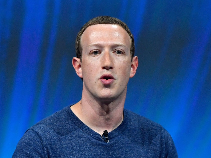 caption: Facebook's CEO Mark Zuckerberg speaks at a trade fair in 2018. The company says it will use artificial intelligence to figure out which of its users have died.