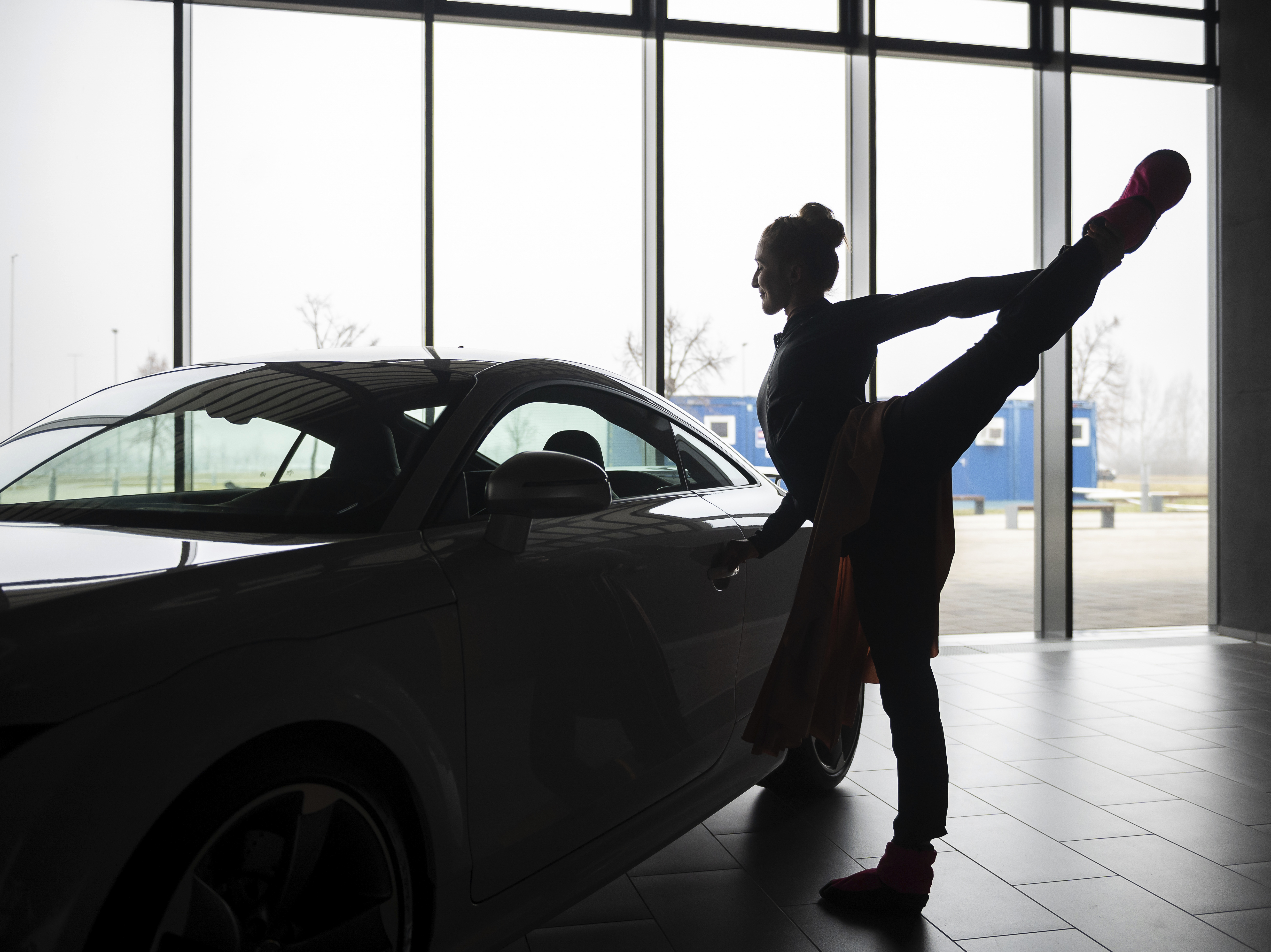 caption: A ballet dancer warms up before an open rehearsal at the Audi automobile factory in Gyor, Hungary, on Thursday. The Ballet Company of Gyor is rehearsing at the factory after being forced to shutter its rehearsal hall in response to soaring energy prices.