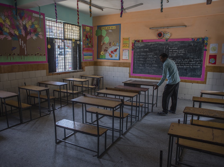 caption: An employee adjusts desks in an empty classroom in New Delhi after schools there were closed in March. A new report finds 1 in 4 countries have either missed their planned school reopening date, or not yet set one.
