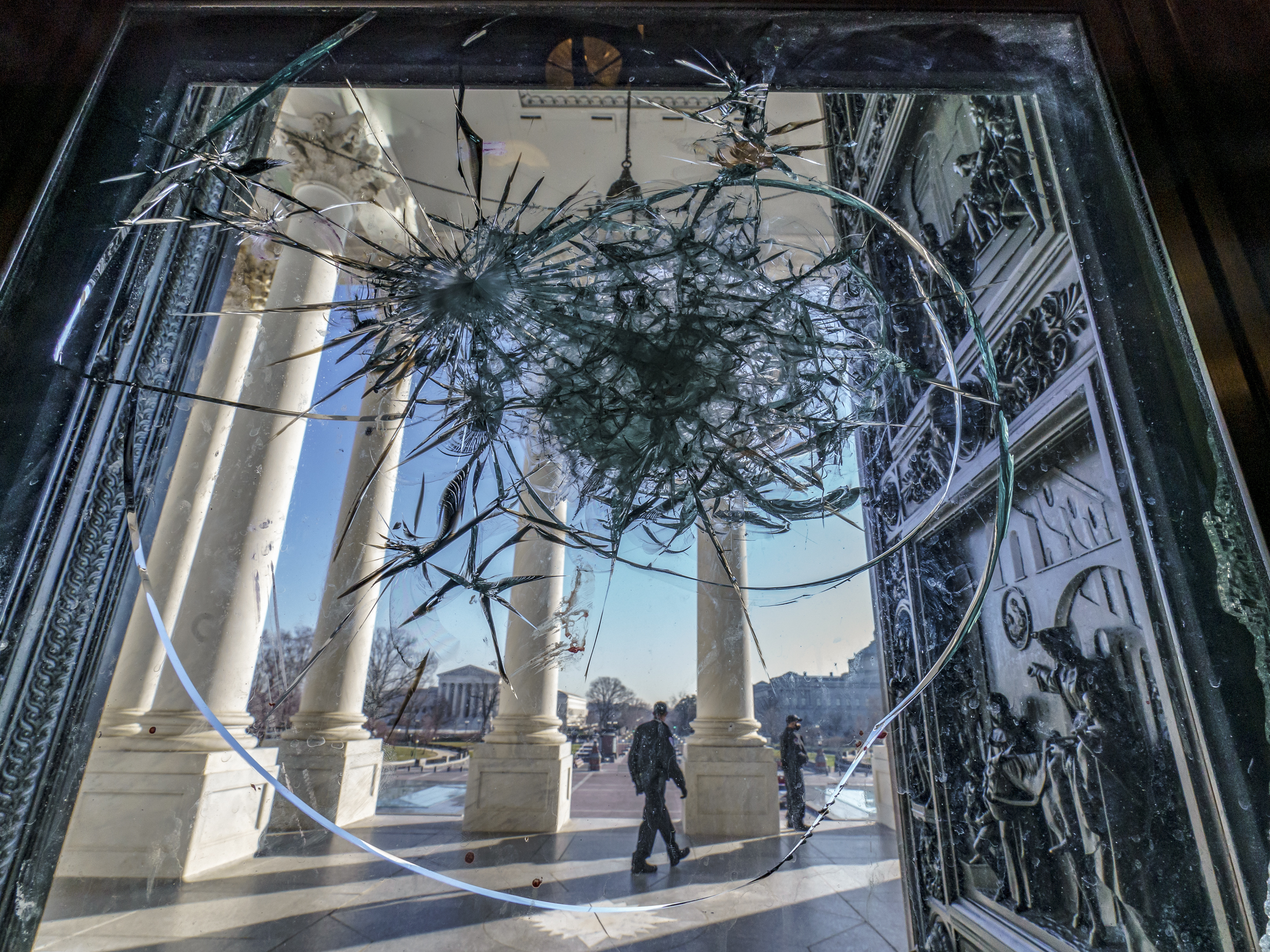 caption: In this Jan. 12 photo, shattered glass from the attack on Congress by a pro-Trump mob is seen in the doors leading to the Capitol Rotunda.