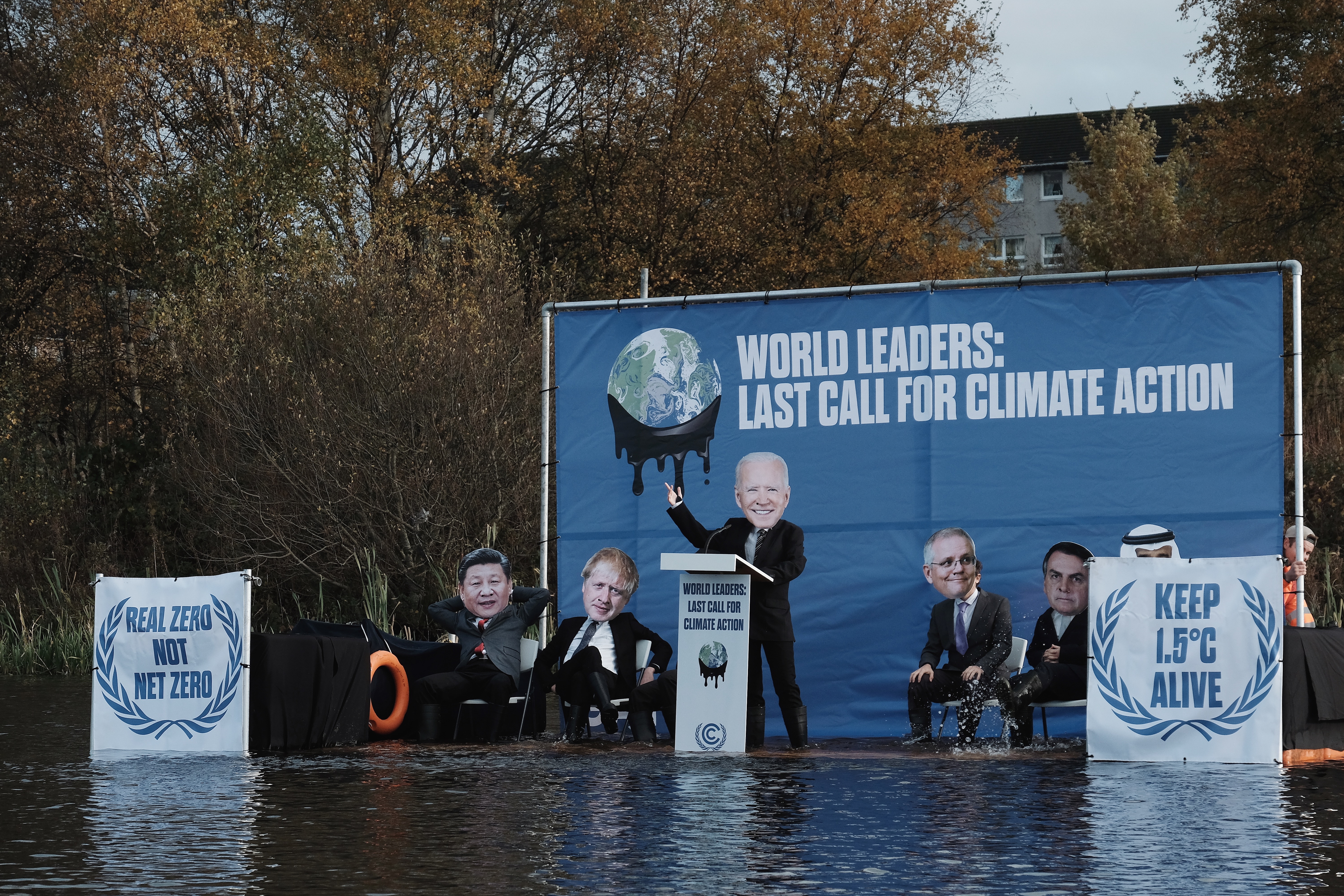caption: "Joe Biden" and other faux world leaders on a submerged stage built by climate activists outside the global climate summit in Glasgow, Scotland