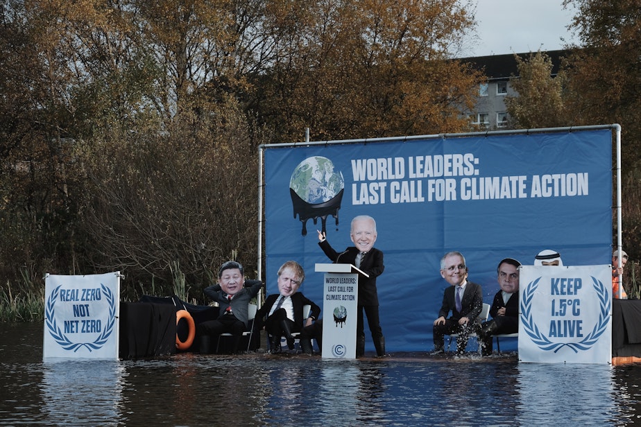 caption: "Joe Biden" and other faux world leaders on a submerged stage built by climate activists outside the global climate summit in Glasgow, Scotland