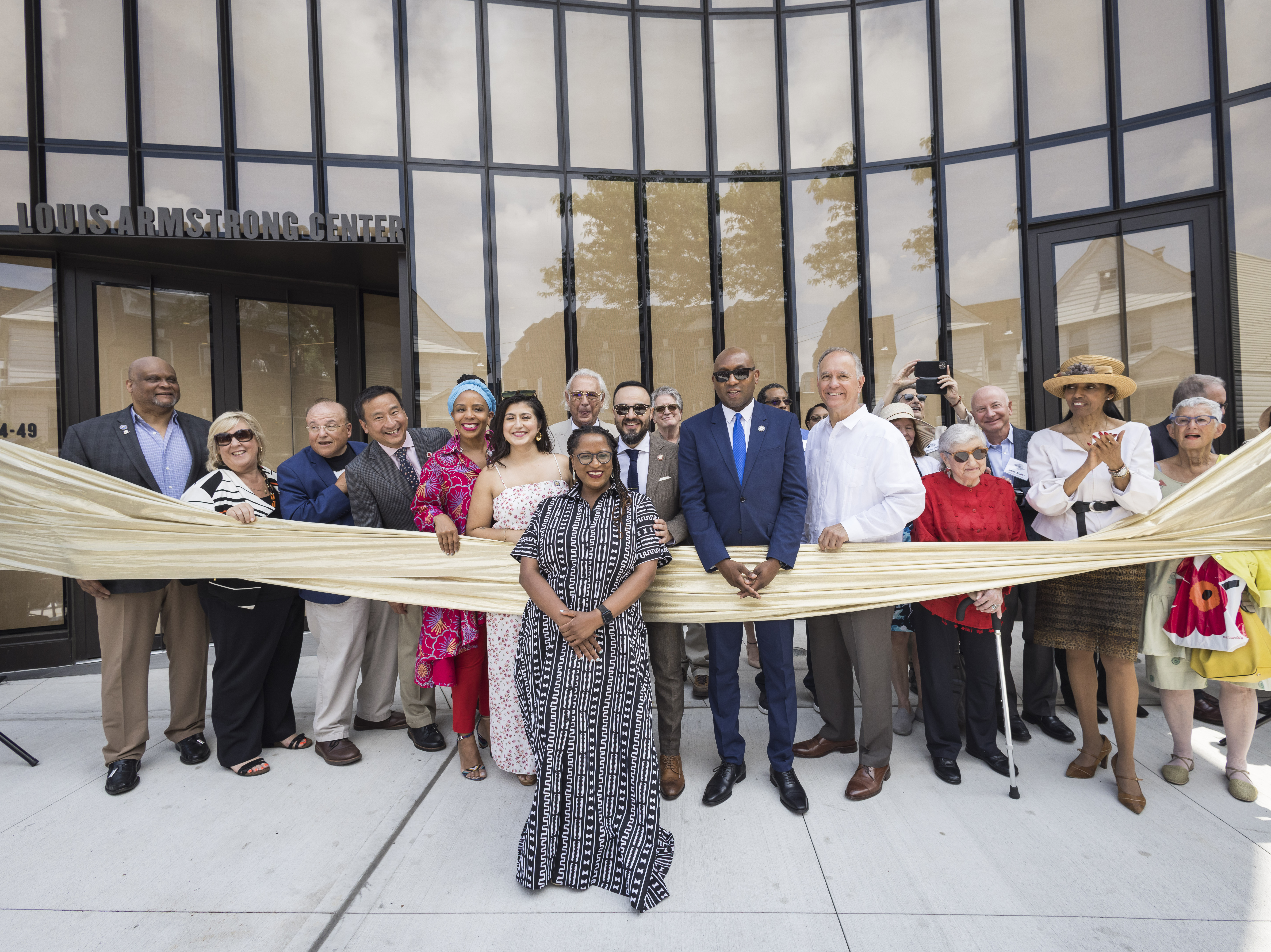 caption: Regina Bain, executive director of the Louis Armstrong House Museum, leads a ribbon-cutting for the brand-new Louis Armstrong Center on June 29 in Queens, New York.