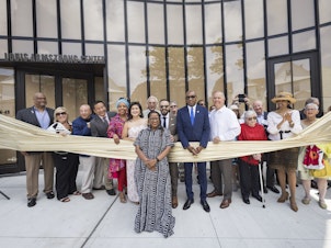 caption: Regina Bain, executive director of the Louis Armstrong House Museum, leads a ribbon-cutting for the brand-new Louis Armstrong Center on June 29 in Queens, New York.