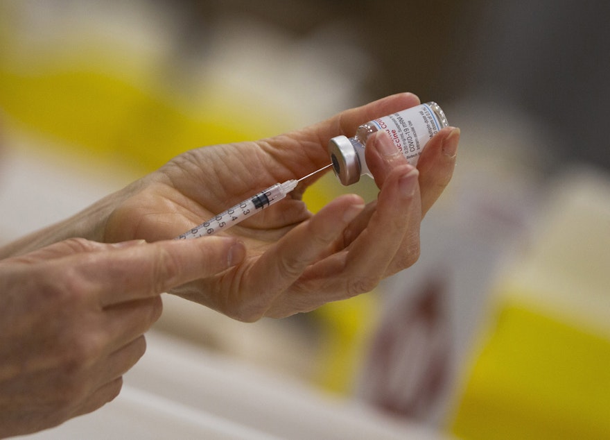 caption: In this file photo dated April 14, 2021, a pharmacist fills a syringe from a vial of the Moderna COVID-19 vaccine in Antwerp, Belgium. (Virginia Mayo/AP FILE)