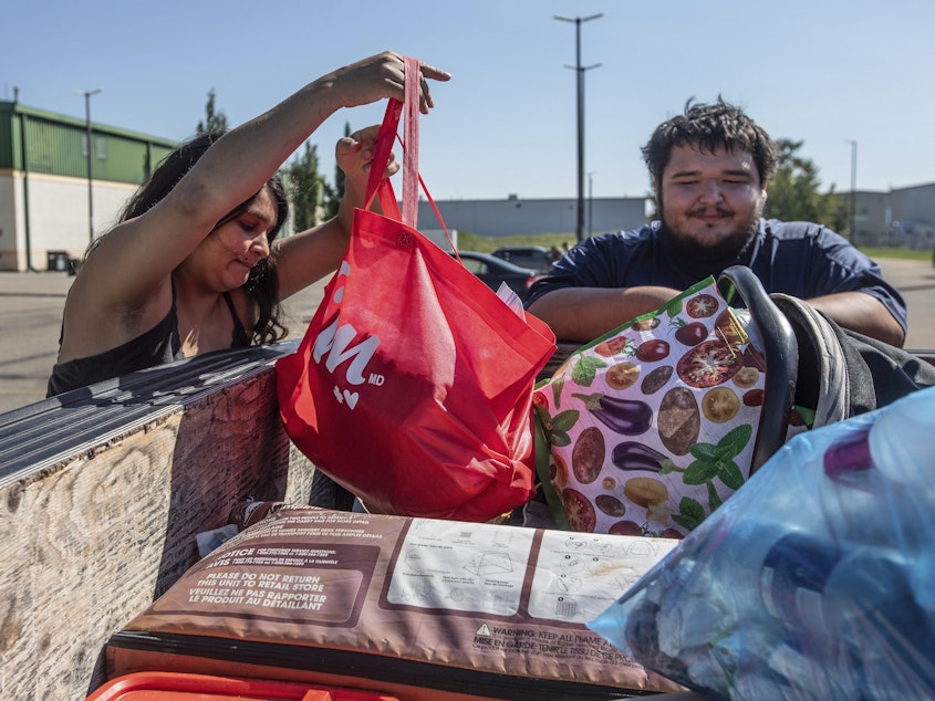 caption: Hay River, N.W.T. fire evacuees Tanisha Edison and her boyfriend Mason Bruneau go through their belongings at the evacuee center in St. Albert, Alberta, on Wednesday, Aug. 16, 2023.