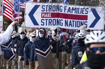 caption: Members of the white supremacist group Patriot Front march on Constitution Avenue near the National Archives in Washington, Friday, Jan. 21, 2022. 