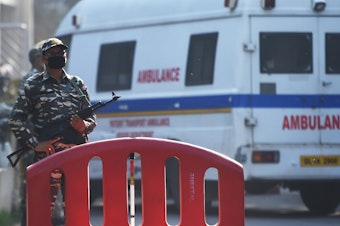 caption: Security personnel stand guard as an ambulance carrying the bodies of four executed men enters Deen Dayal Upadhyay hospital in New Delhi Friday.